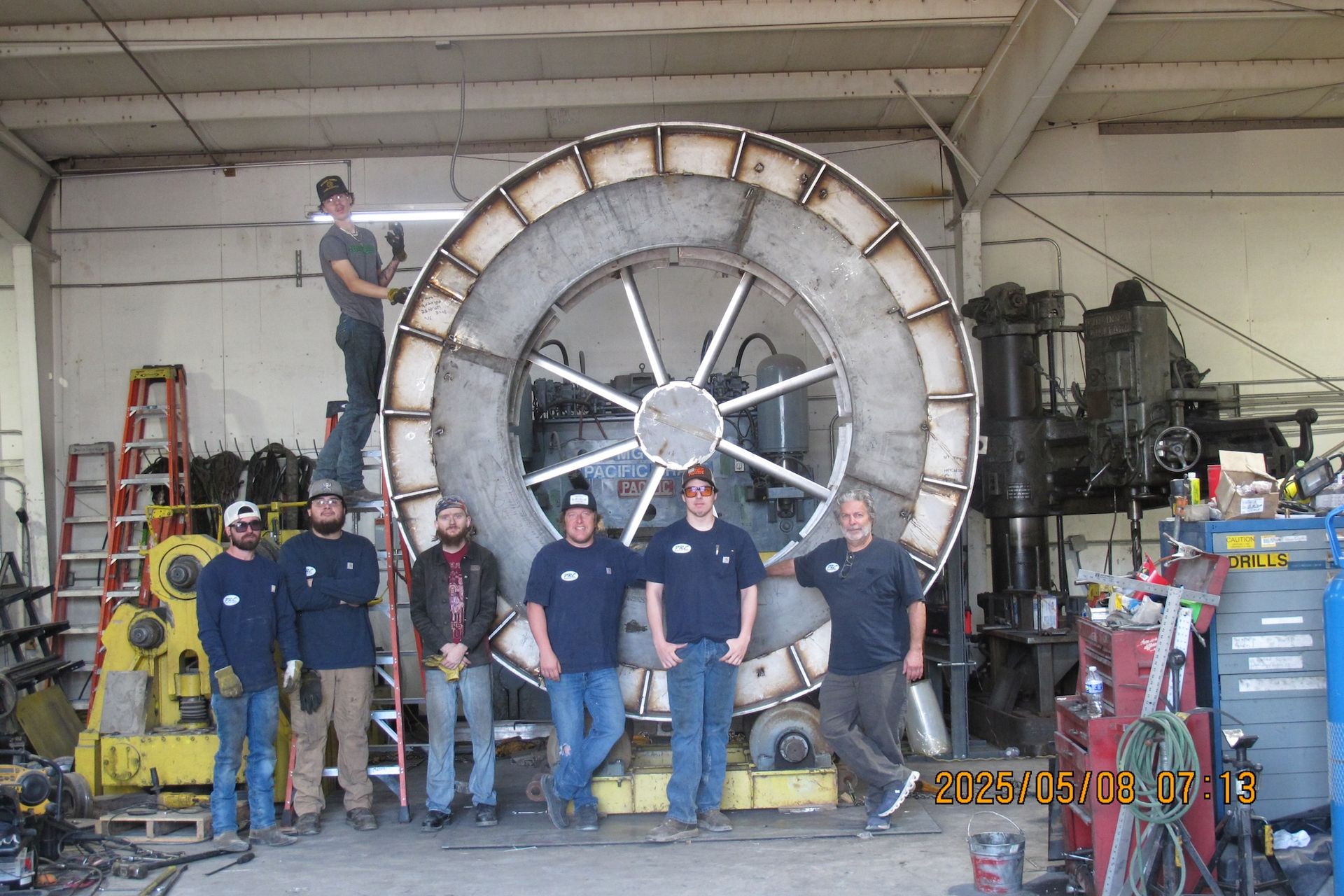 A group of men standing in front of a large wheel