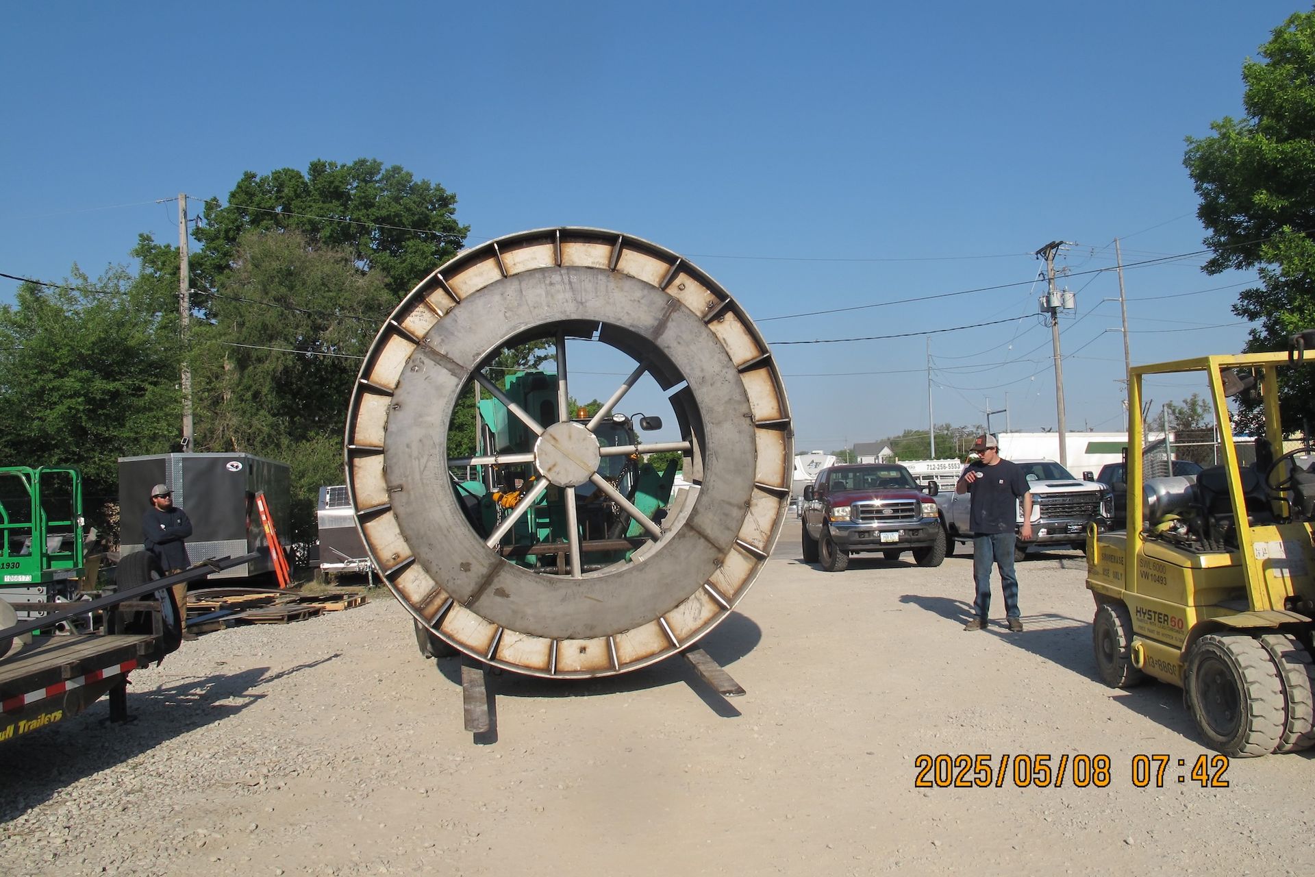 A large spool of metal is sitting in a parking lot