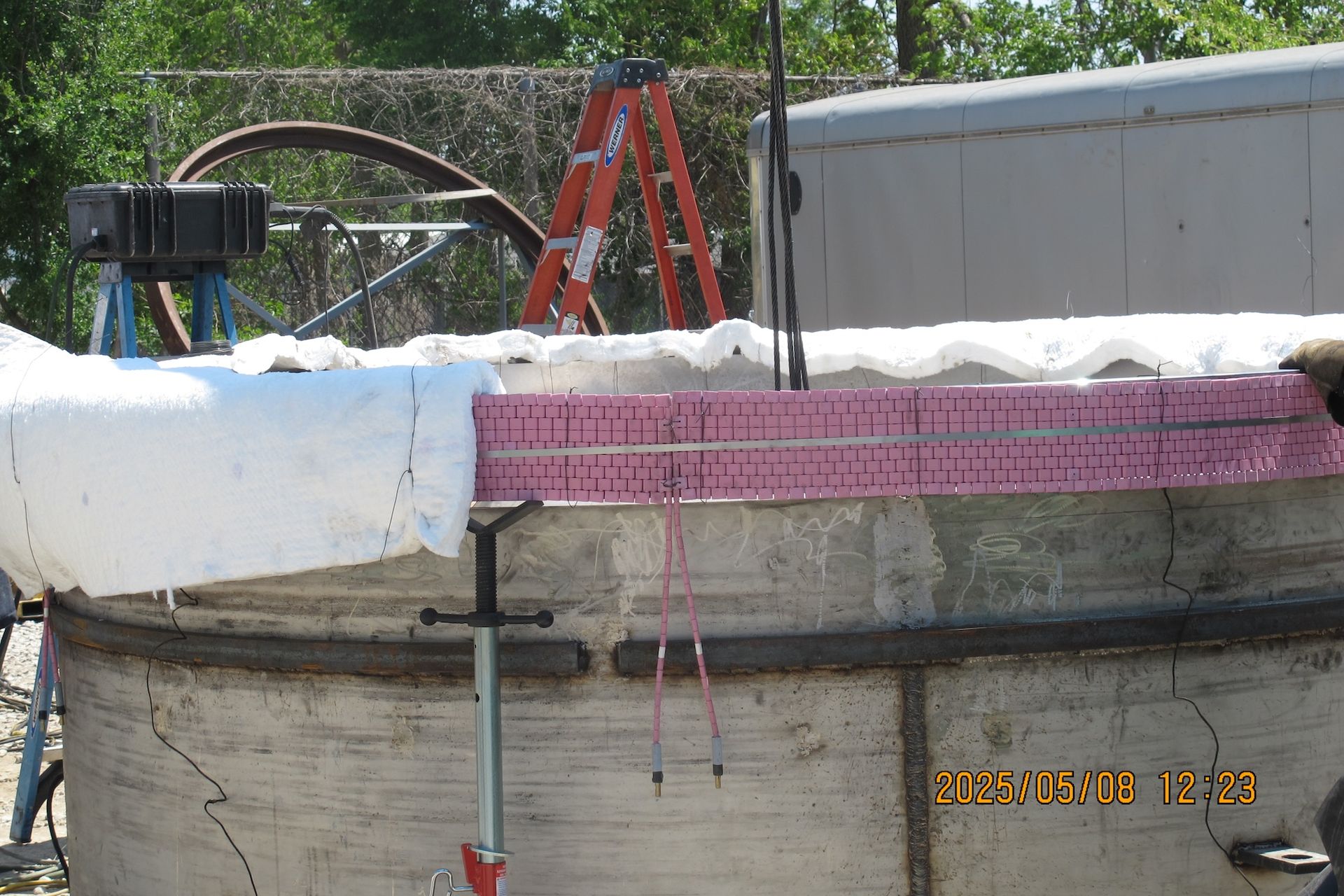 A concrete wall with a ladder in the background and a photo taken at 12:59