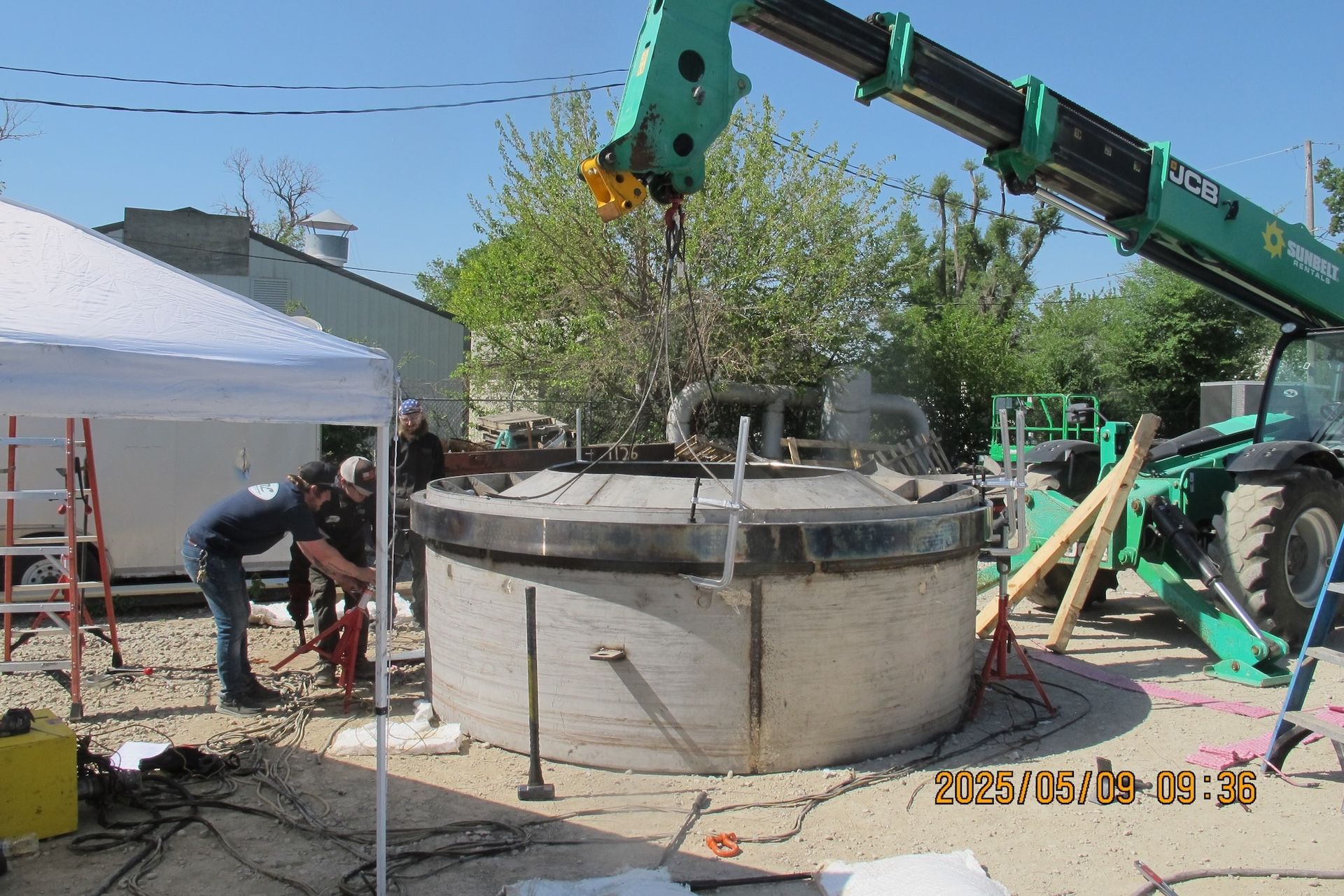 A green crane is lifting a large concrete object