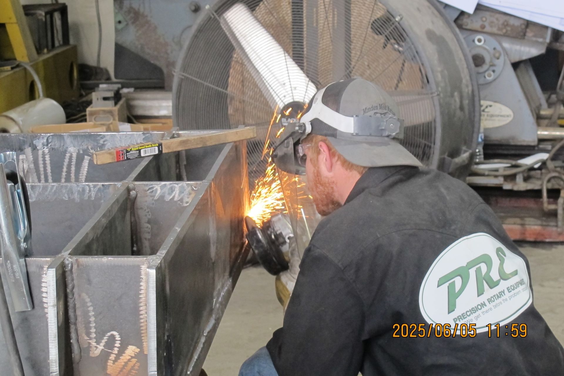 A man wearing a pro shirt is welding a piece of metal