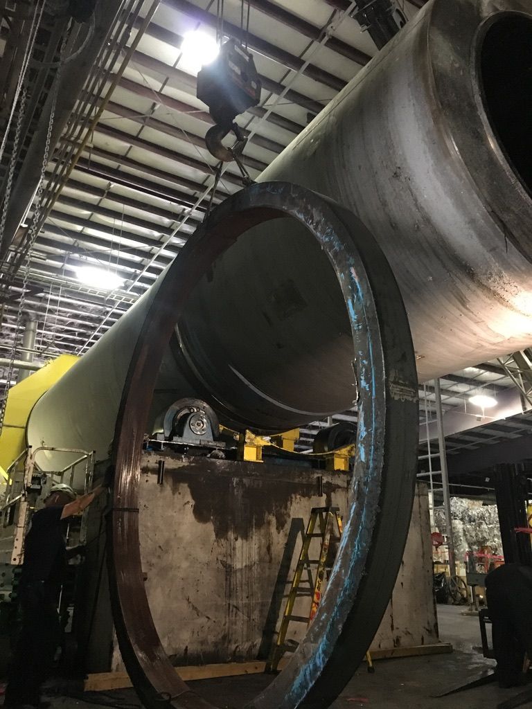 A large metal pipe is being worked on in a factory.