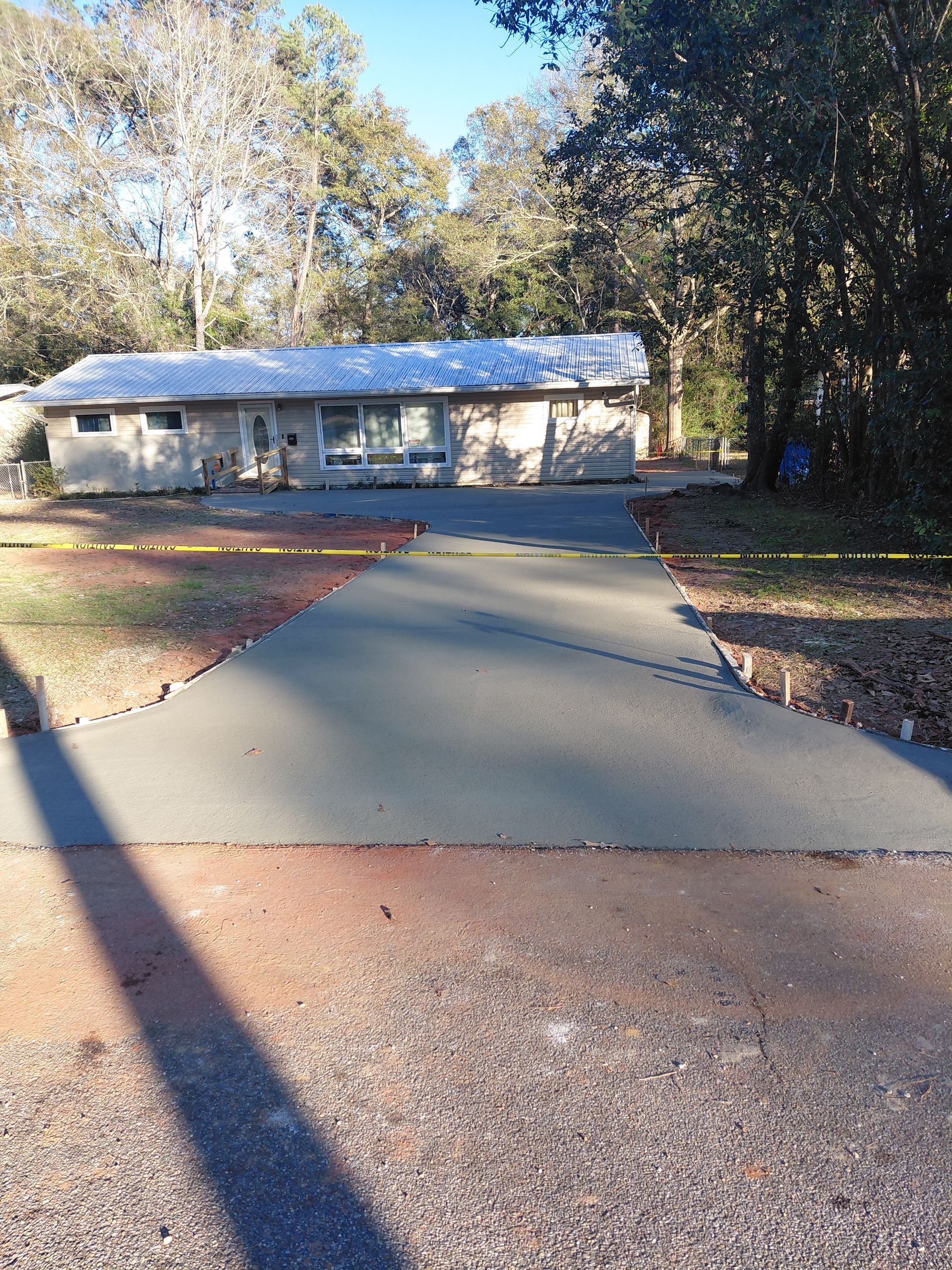 Newly poured concrete driveway leading to a one-story house.