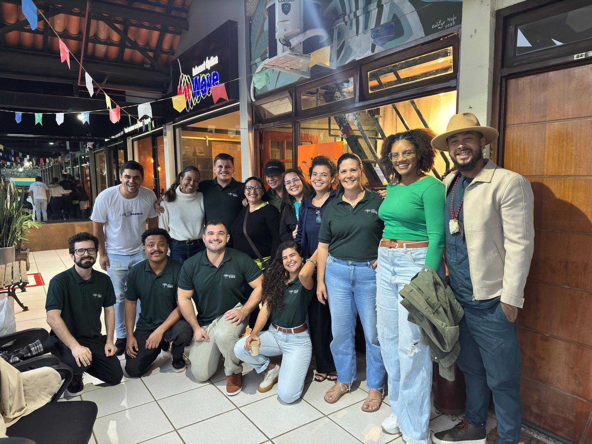 Foto de grupo ao ar livre, pessoas sorridentes em diversas roupas casuais.