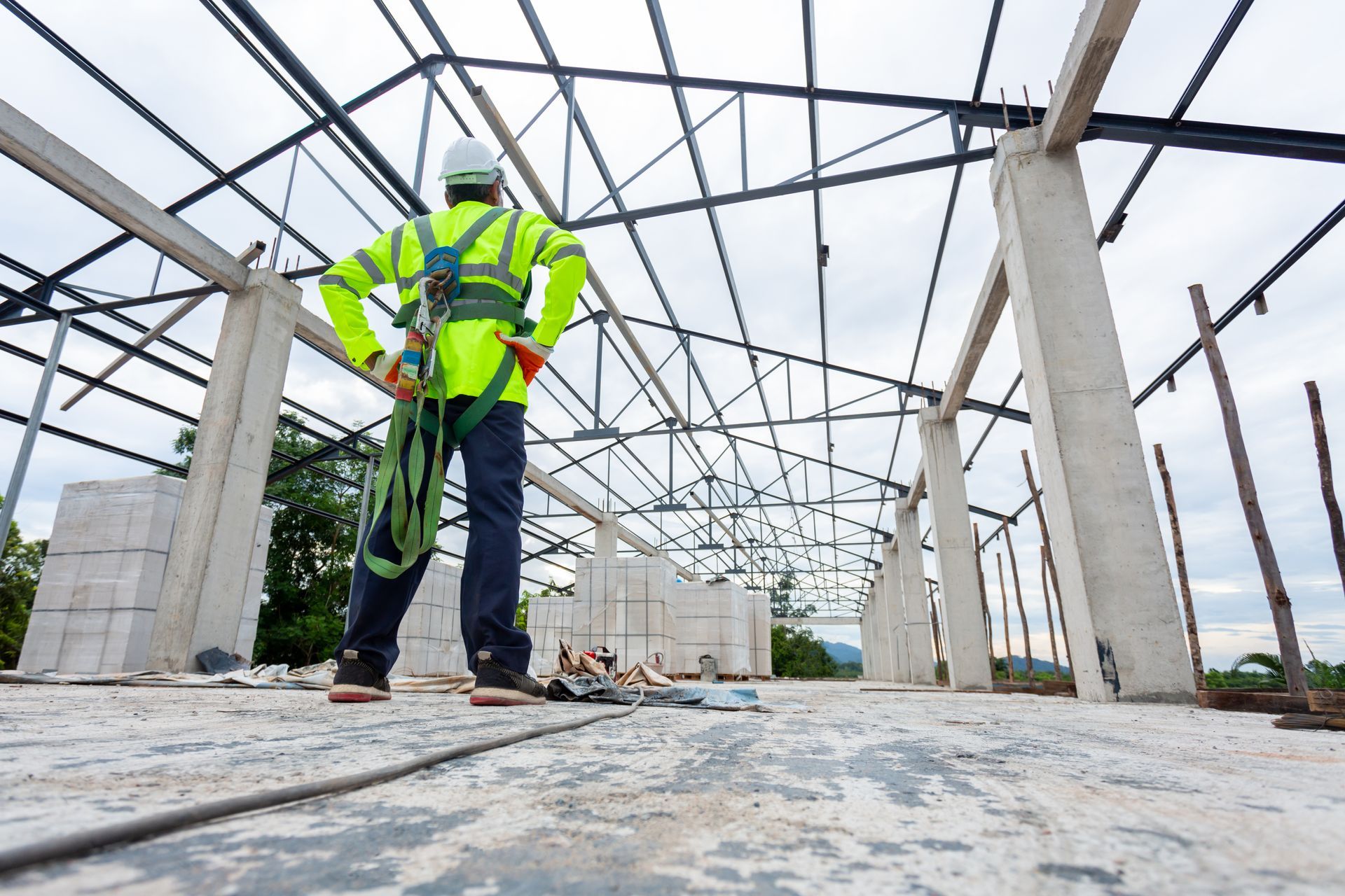 A construction worker is standing in the middle of a building under construction.