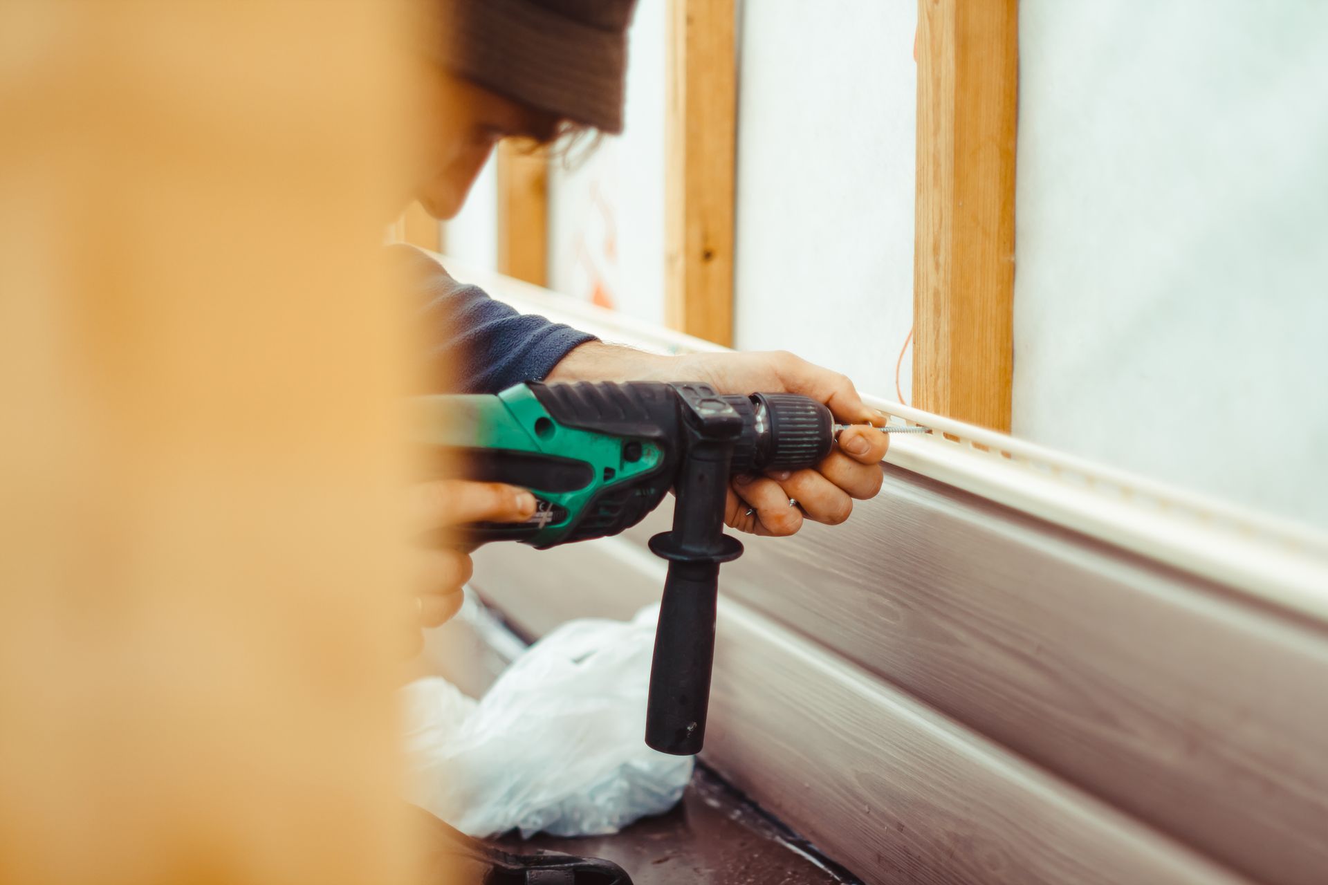 A man is using a drill to drill a hole in a wall.
