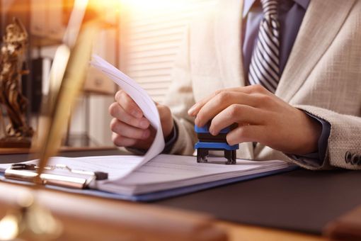 Person stamping a document at a desk in warm office light