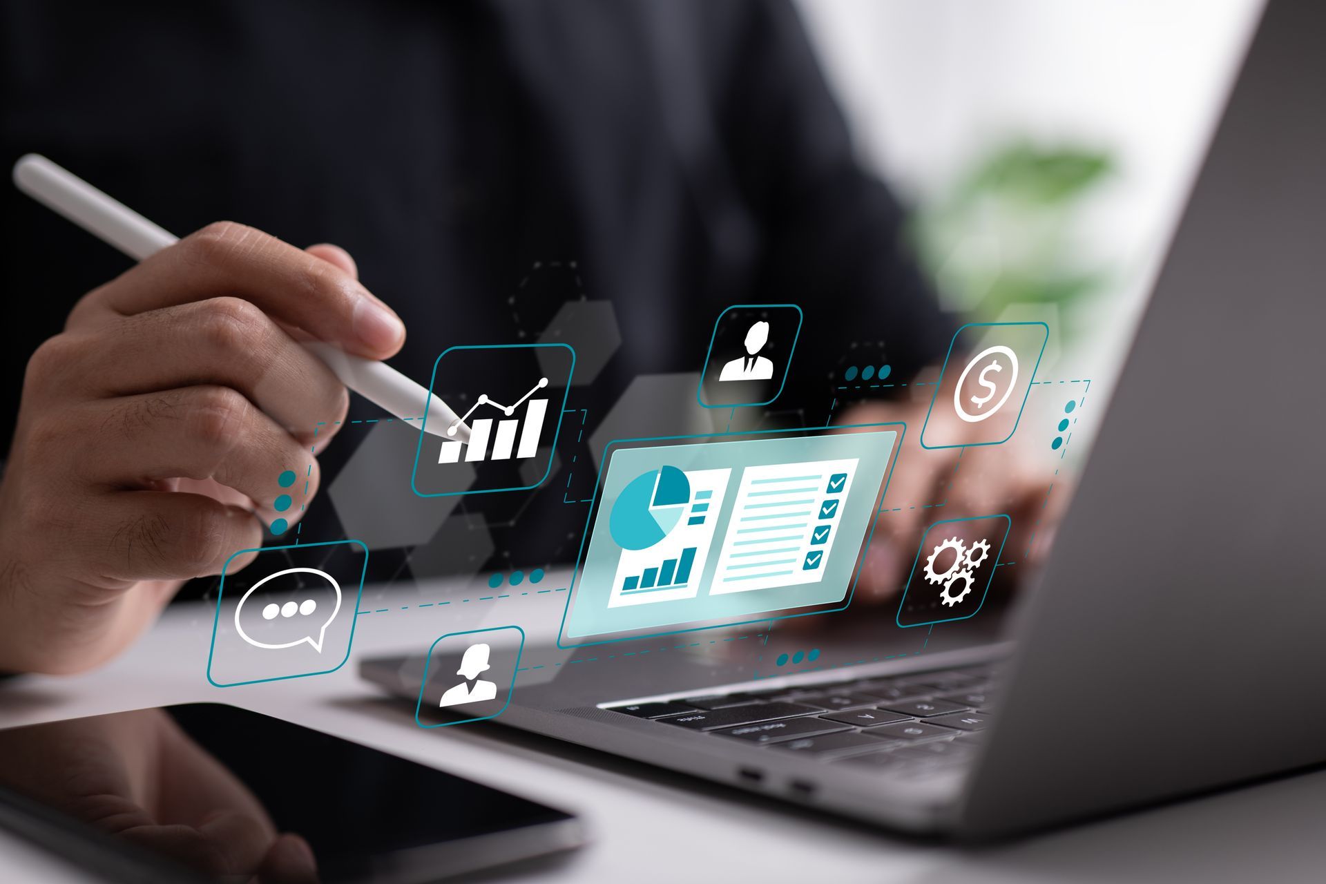 Person using a stylus on a laptop with floating digital interface icons and charts