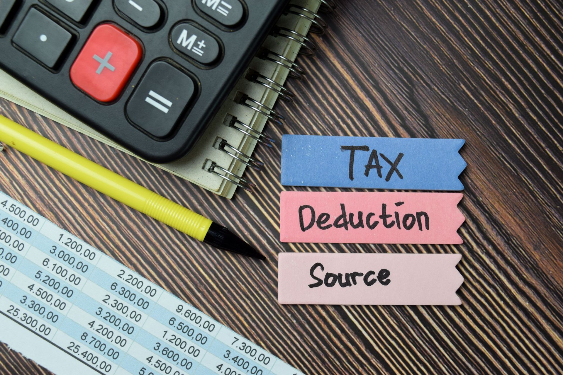 Tax deduction notes beside calculator, pencil, and tax form on desk