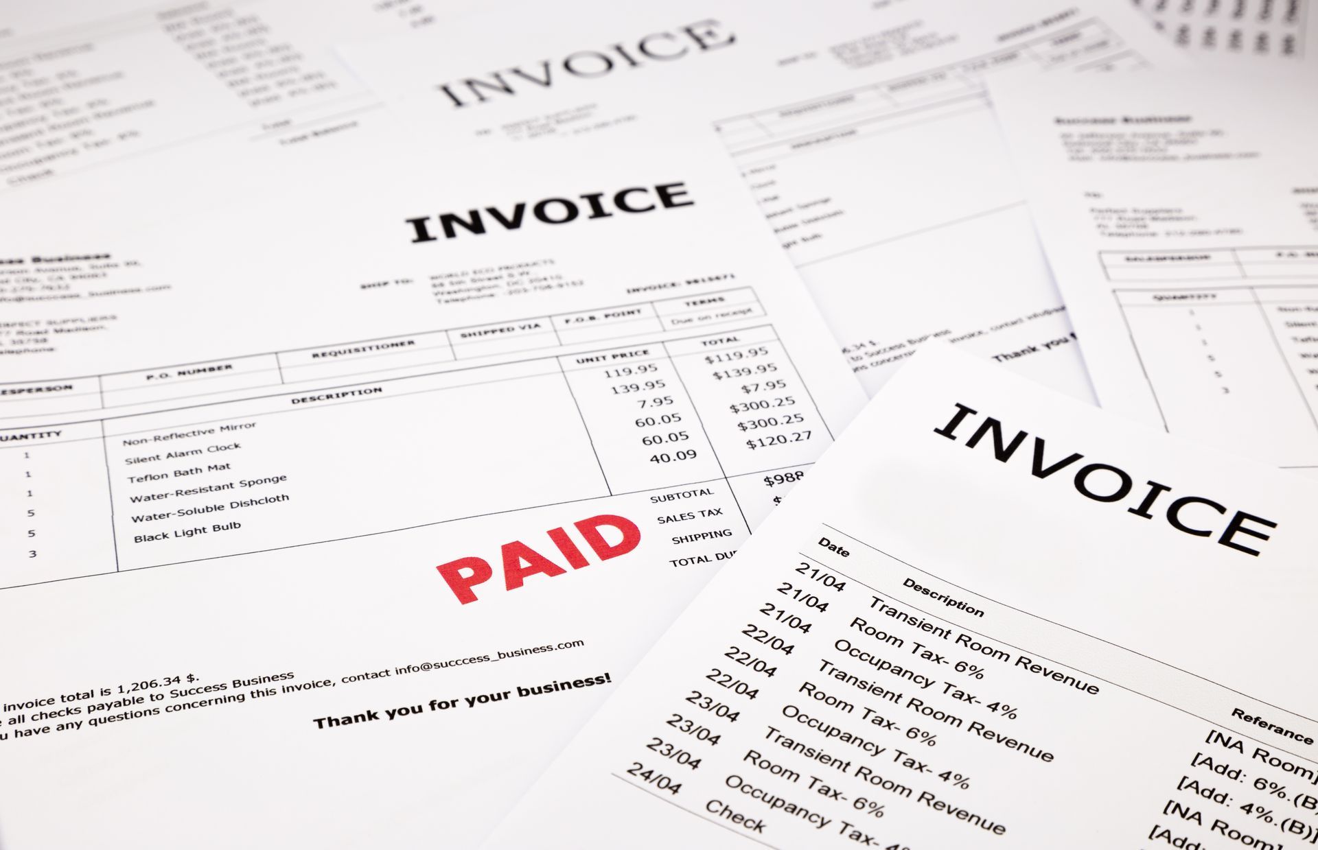 Scattered invoice documents with bold “INVOICE” headers and a red “PAID” stamp