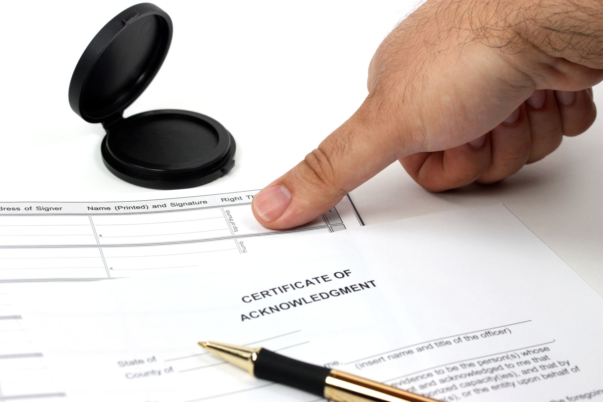 Hand stamping a certificate with an open ink stamp and pen on a white desk