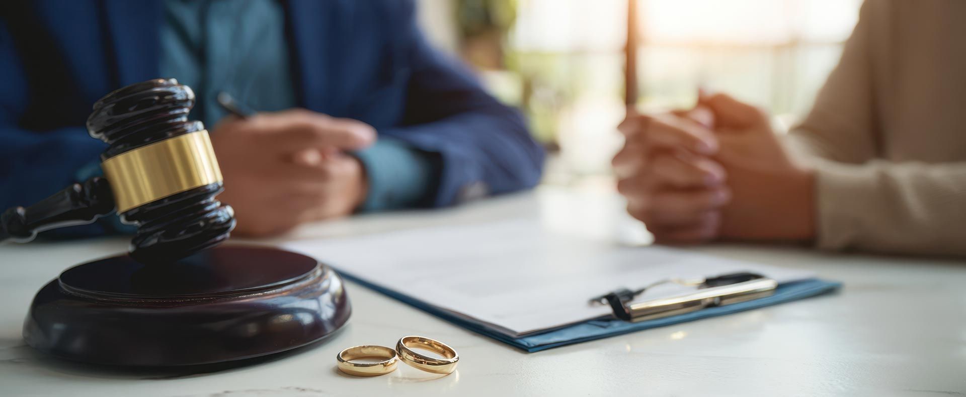 Divorce attorney meeting with couple beside gavel wedding rings and legal documents. Divorce attorney meeting with couple beside gavel wedding rings and legal documents.