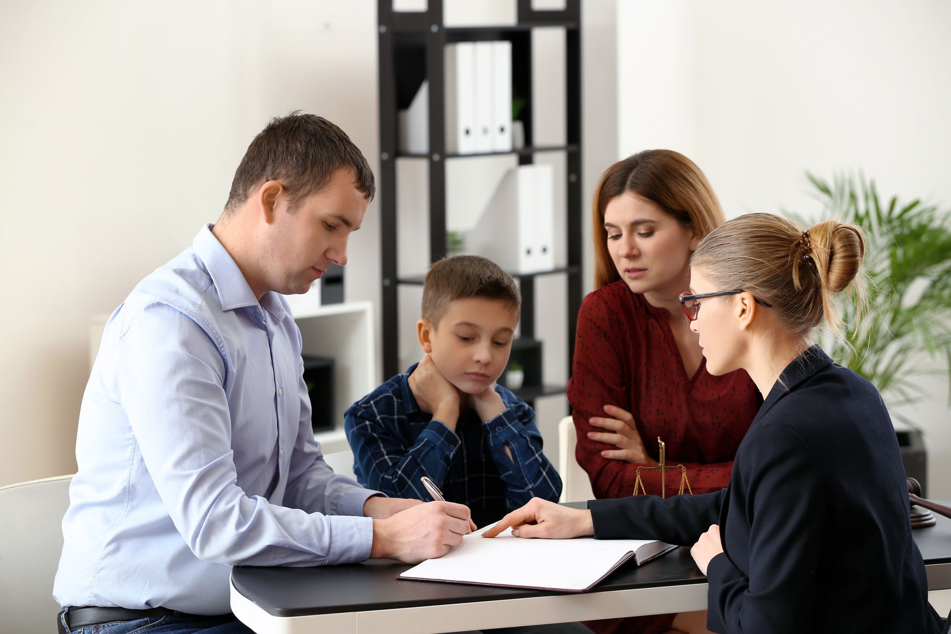 Family meeting with child custody lawyer, signing important legal papers at a table.