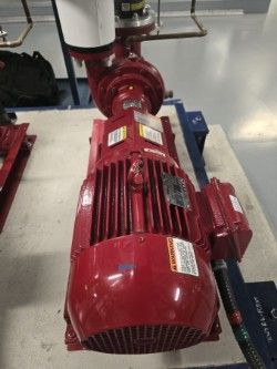 Pompe et moteur industriels rouges sur un sol en béton.