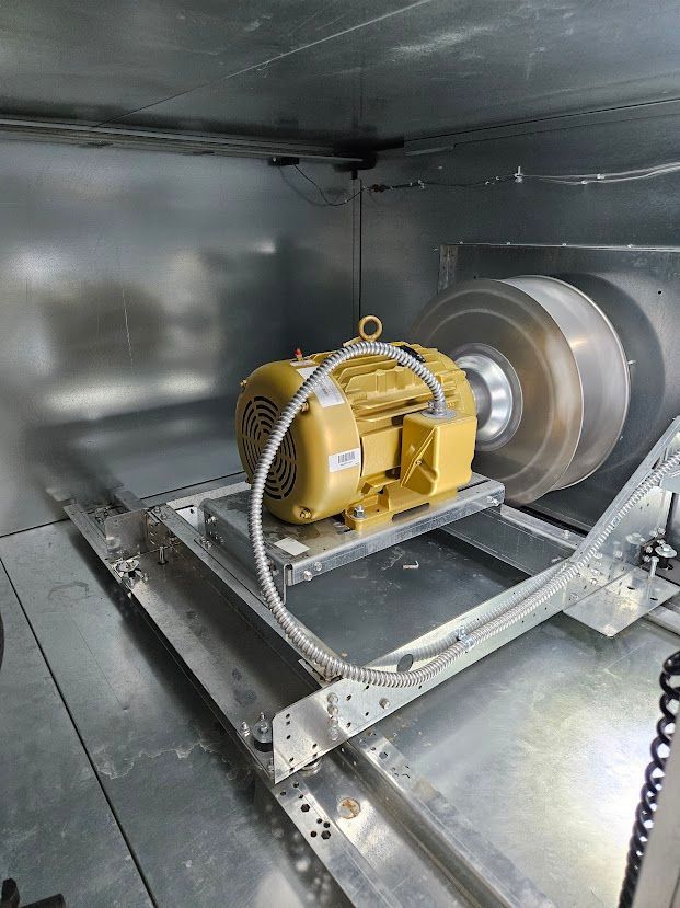 Moteur électrique jaune sur une plateforme de test à l'intérieur d'une chambre métallique.