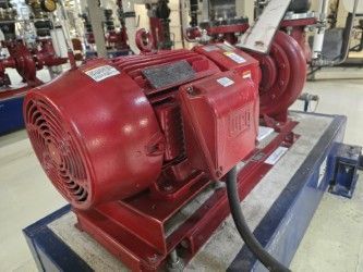 Pompe industrielle rouge avec moteur sur un socle bleu.
