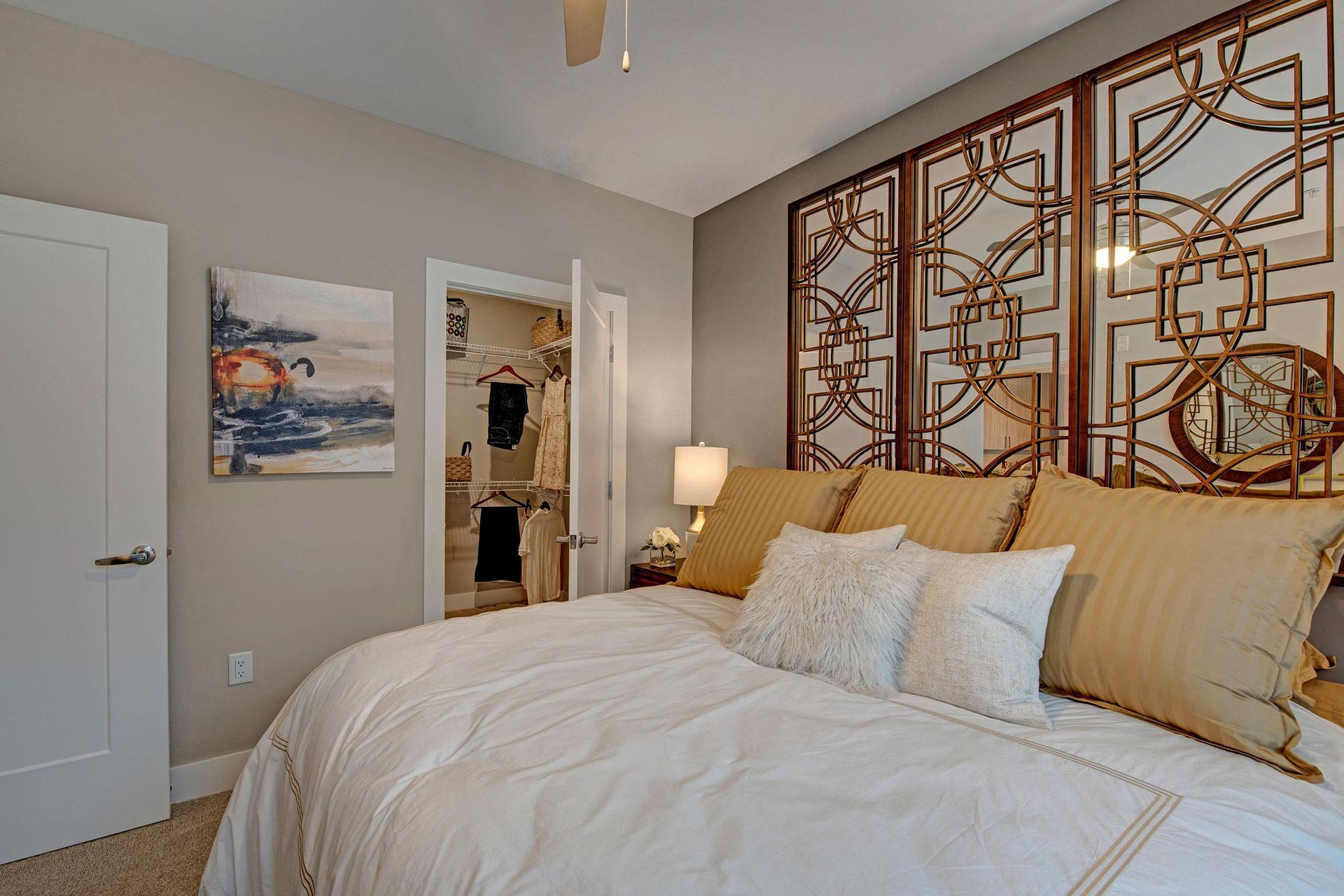 Bedroom with bed, decorative headboard, closet, artwork, and lamp.