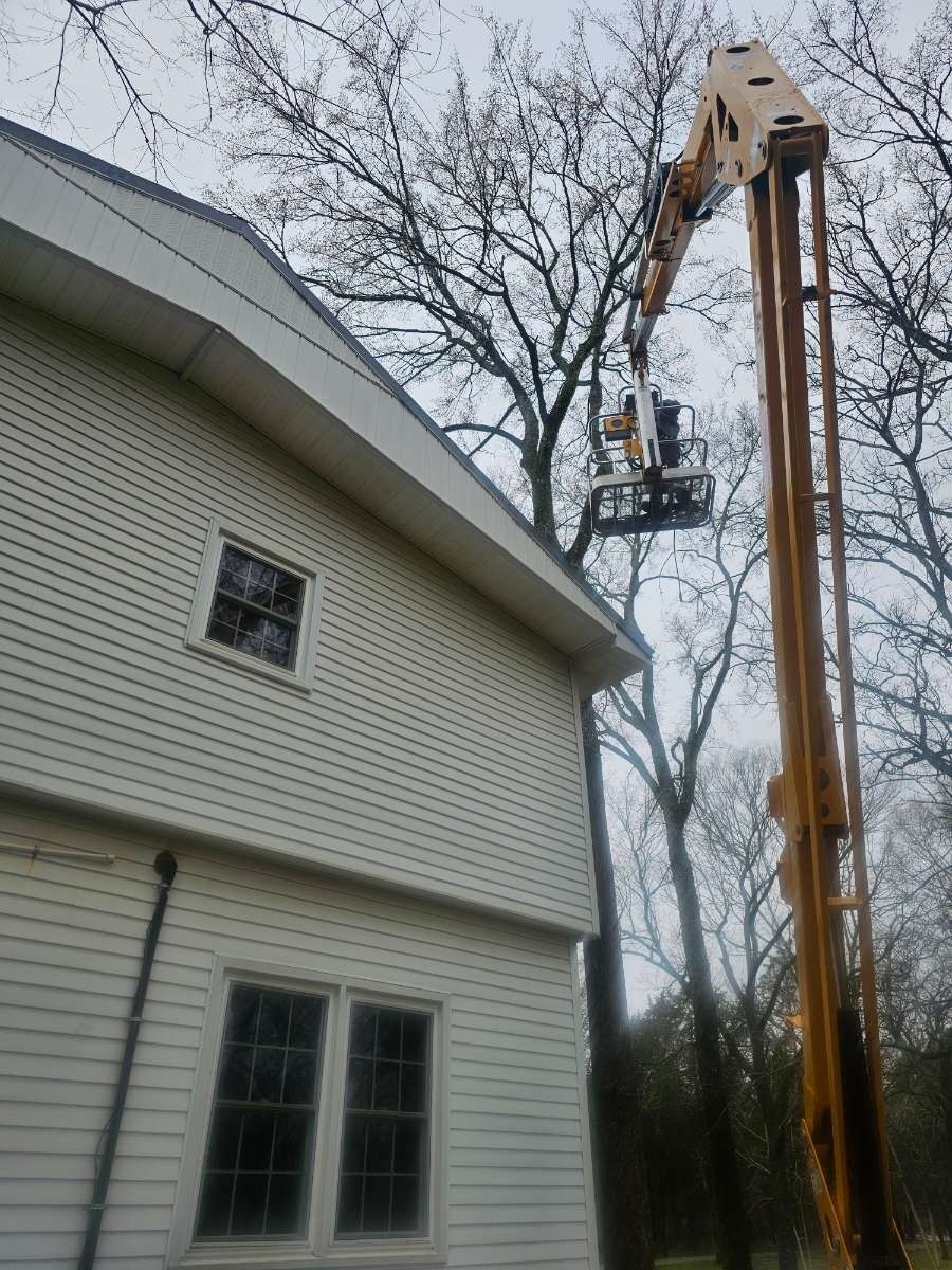 Crane lifting equipment beside a white house under bare trees
