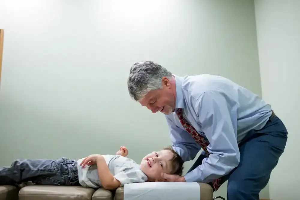 Doctor examining a child lying on an exam table in a clinic room