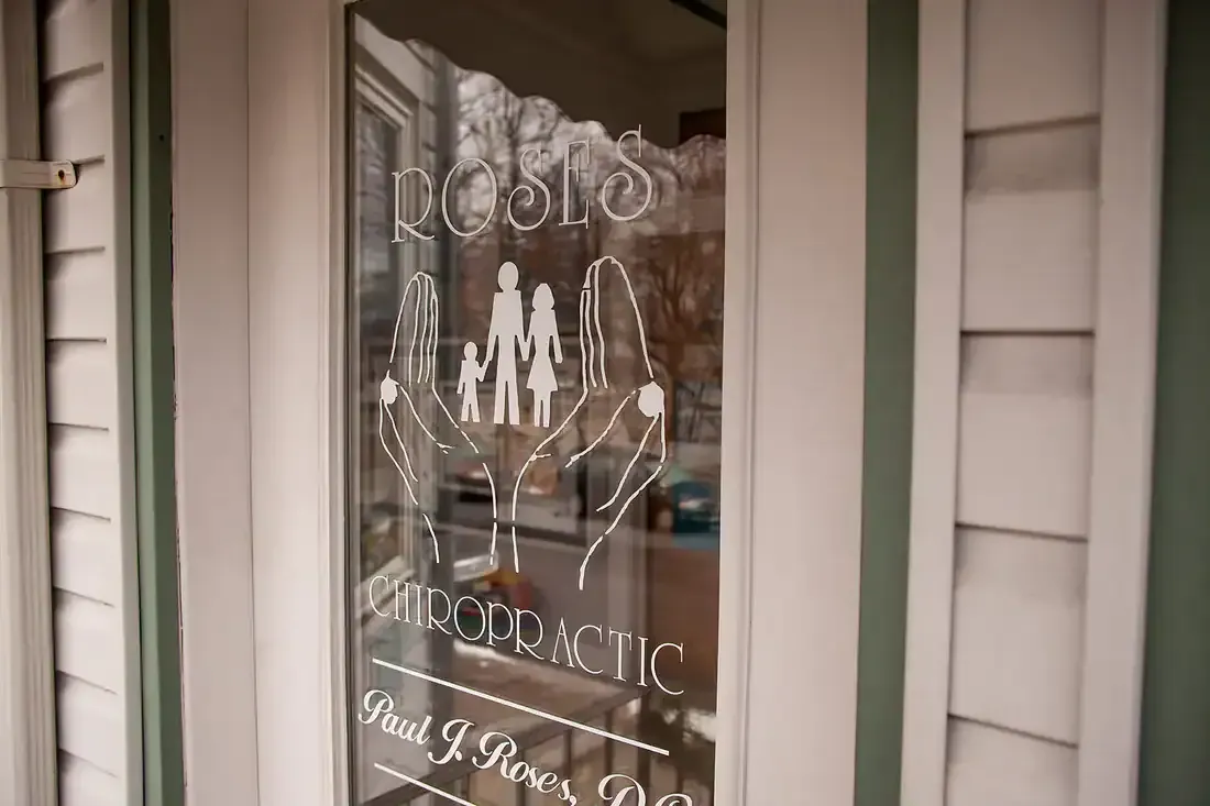 White front door with decorative glass panel and etched “welcome” style lettering on a porch