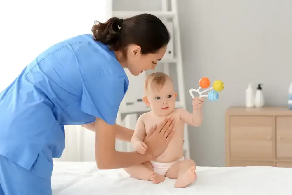 Nurse checking a baby’s chest in a bright nursery, with a toy rattle nearby