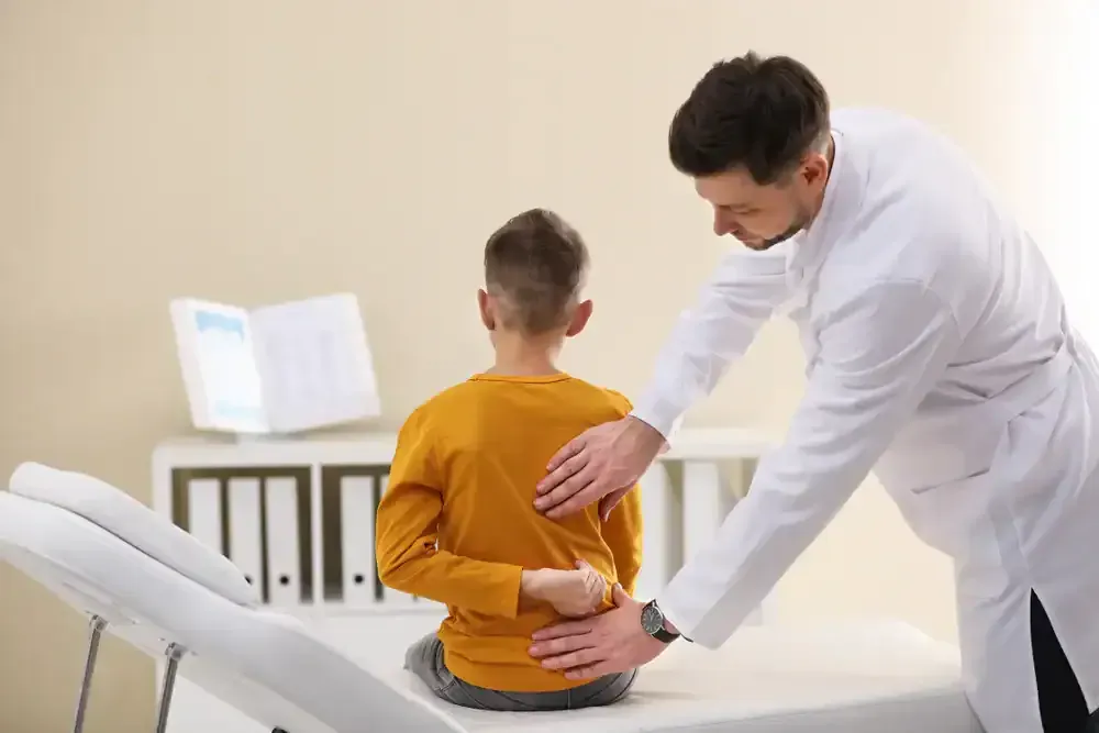 Doctor examining a child’s back in a clinic room