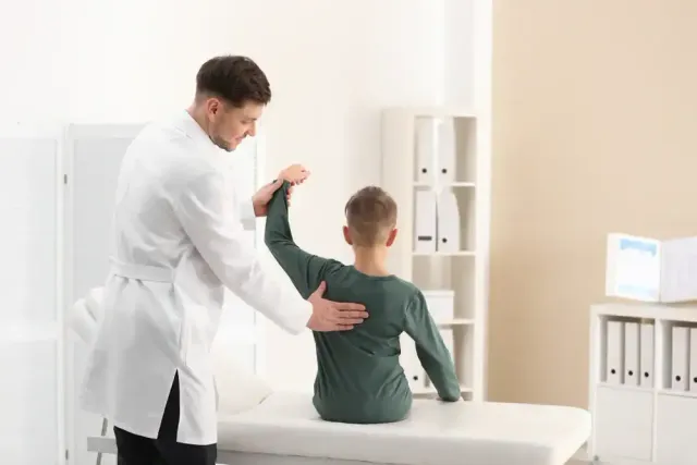 Doctor examining a child’s back in a bright clinic room