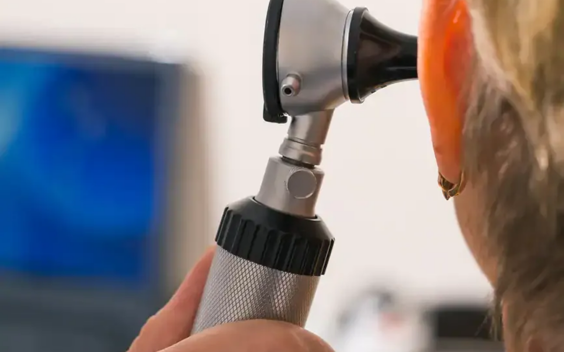 Doctor examining an ear with an otoscope in a clinic