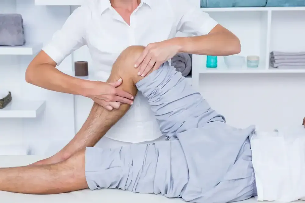 Physical therapist stretching a patient’s leg on a treatment table in a bright clinic