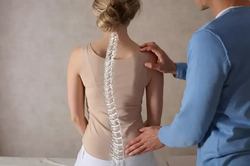 Doctor examining a patient’s spine from behind, with a visible scoliosis pattern marked on the back