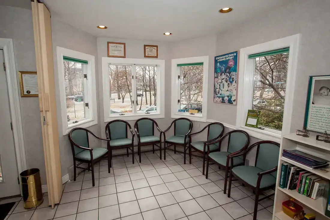 Waiting room with teal chairs, tiled floor, and large windows overlooking snowy trees