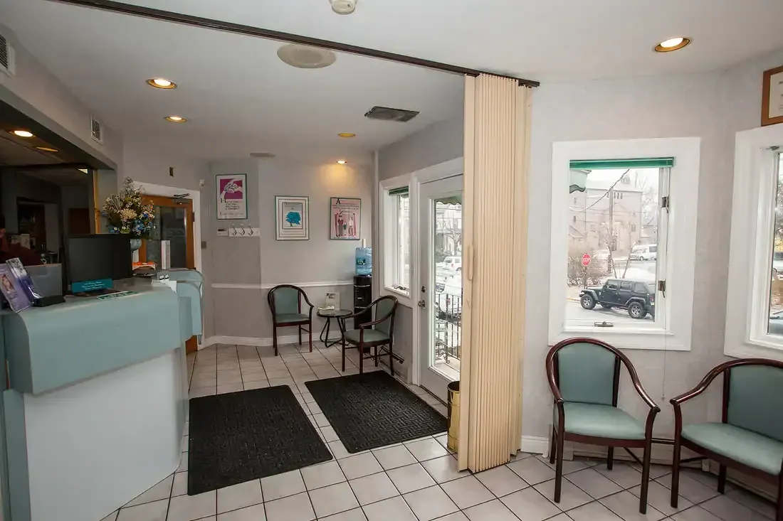 Bright waiting room with tiled floor, mint counters, chairs, and large windows with curtains.