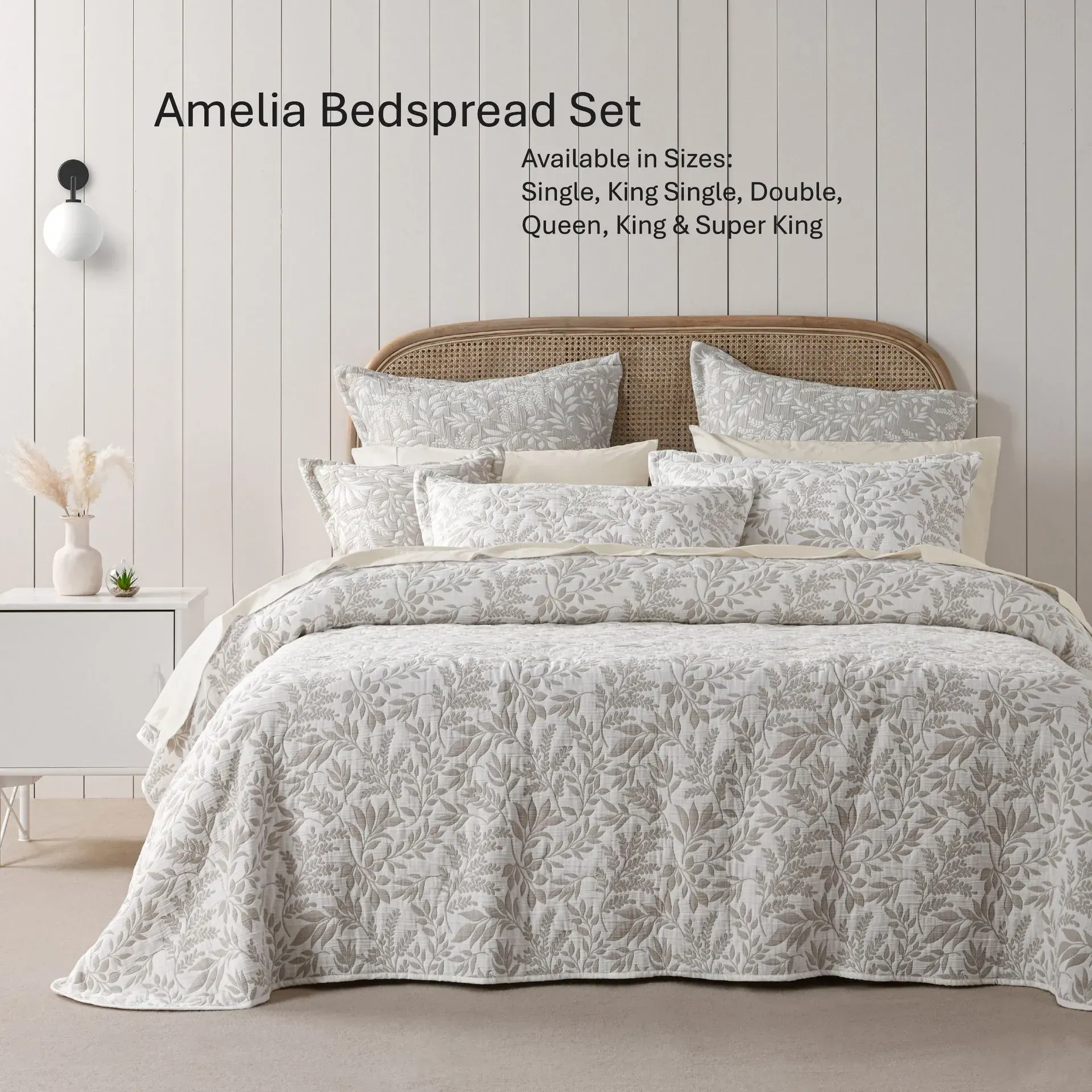 Cream bedspread set on a wicker bed in a bright bedroom, shown in a white floral pattern.
