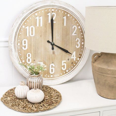 Rustic white wall clock on a shelf beside a small vase, pumpkins, and a tan basket