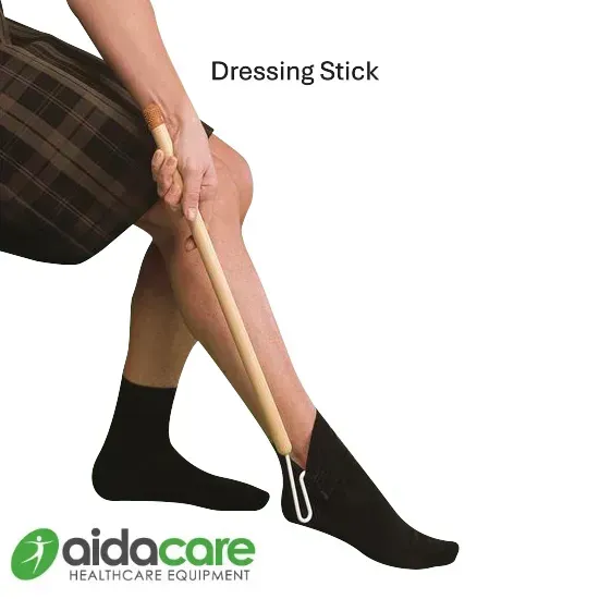 Person using a wooden dressing stick to pull on a black sock; Aidacare product image.