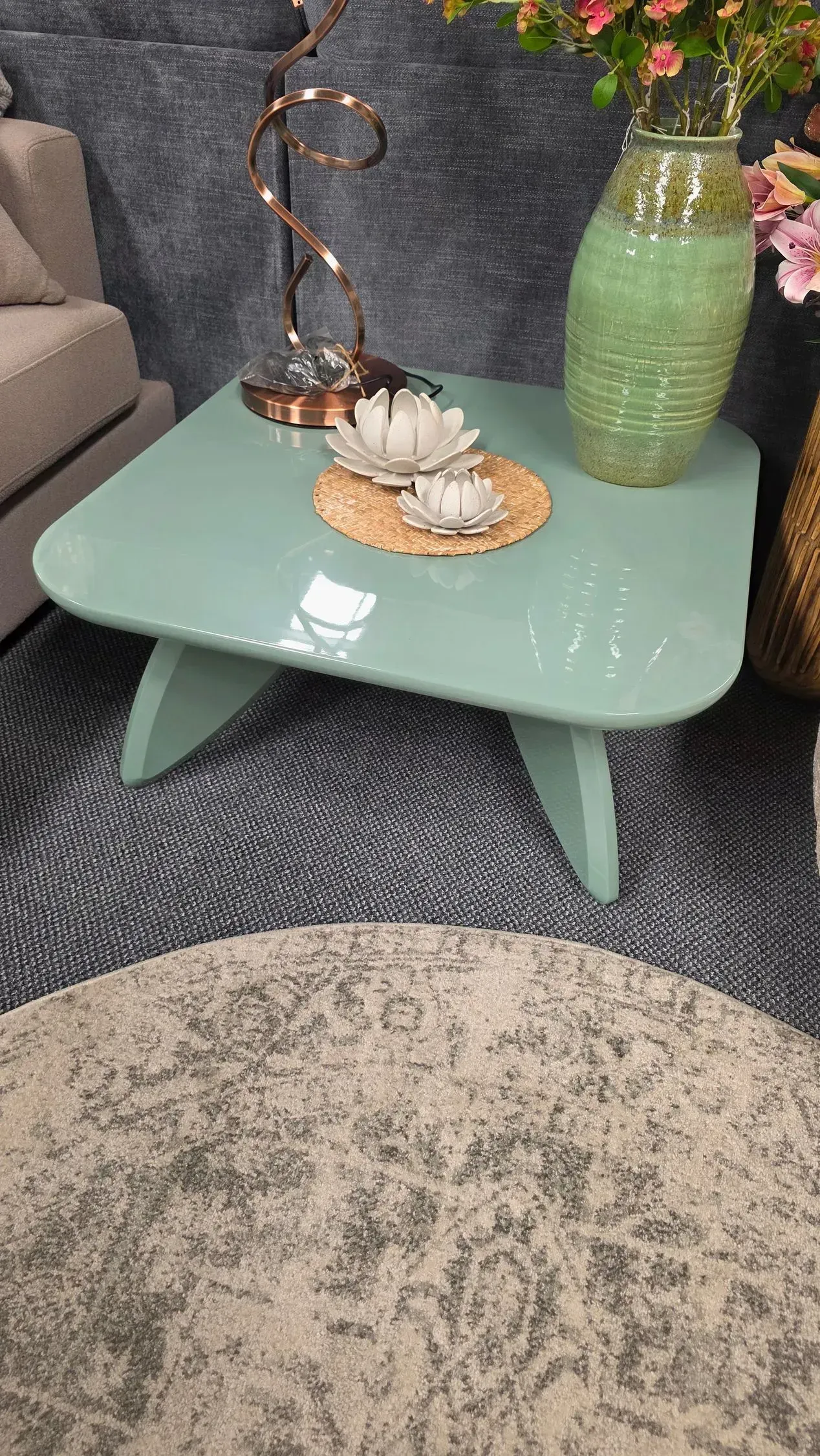 Mint-green coffee table with a decorative bowl and vase in a cozy living room corner