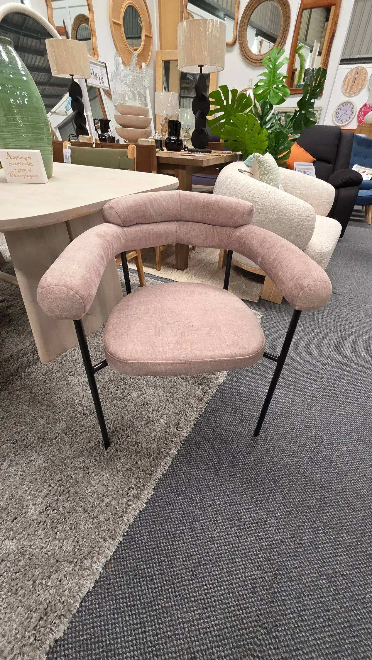 Pink upholstered chair with black legs in a furniture showroom