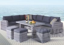 Gray wicker outdoor sectional sofa set with table, cushions, and ottomans by the water