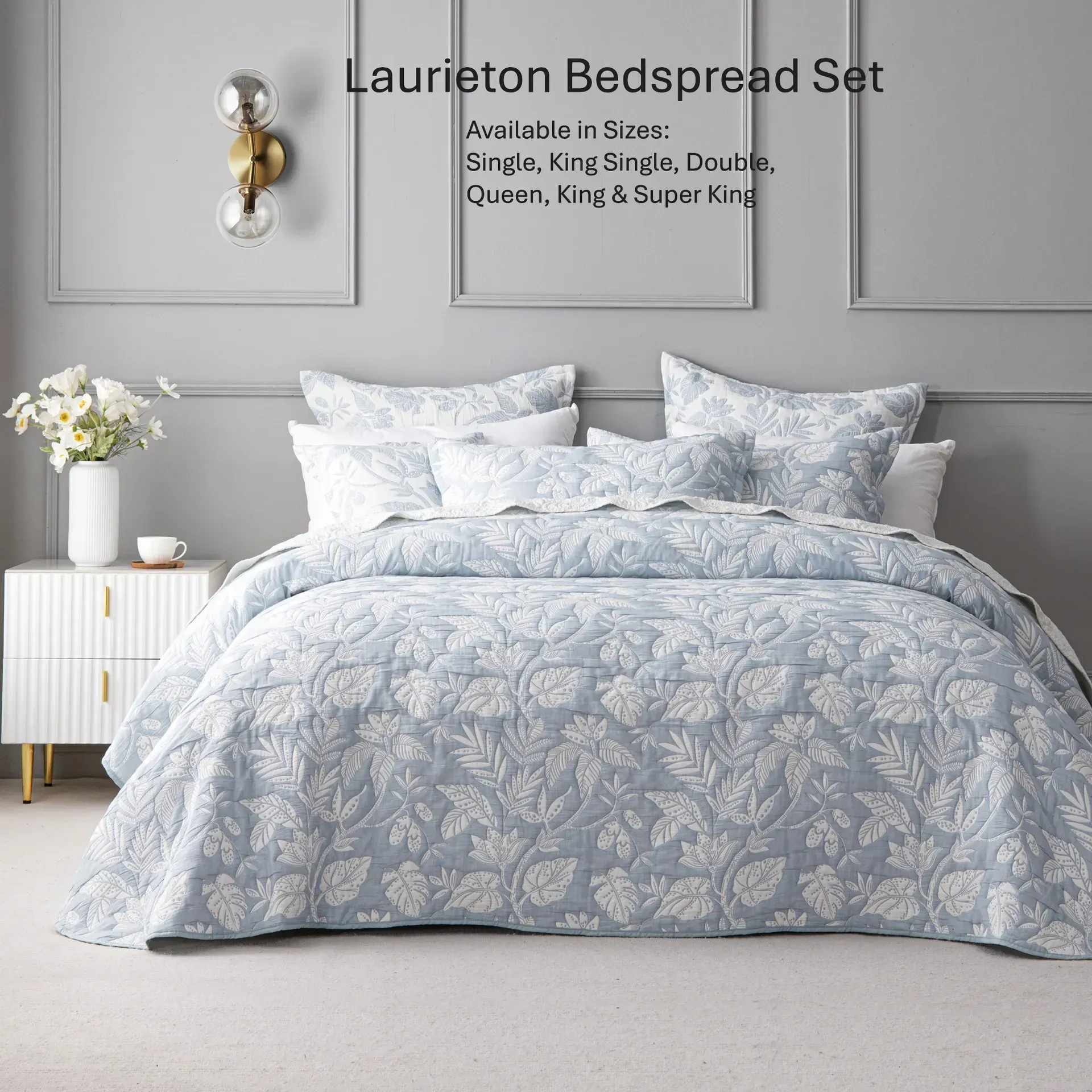 Light blue floral bedspread set on a neatly made bed in a gray bedroom, with white nightstand and flowers