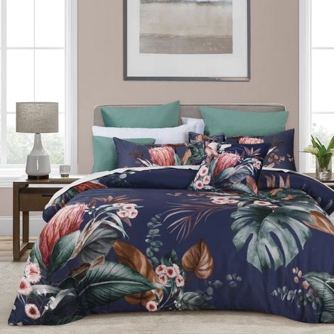 Floral navy bedding on a neatly made bed with teal pillows in a bright bedroom