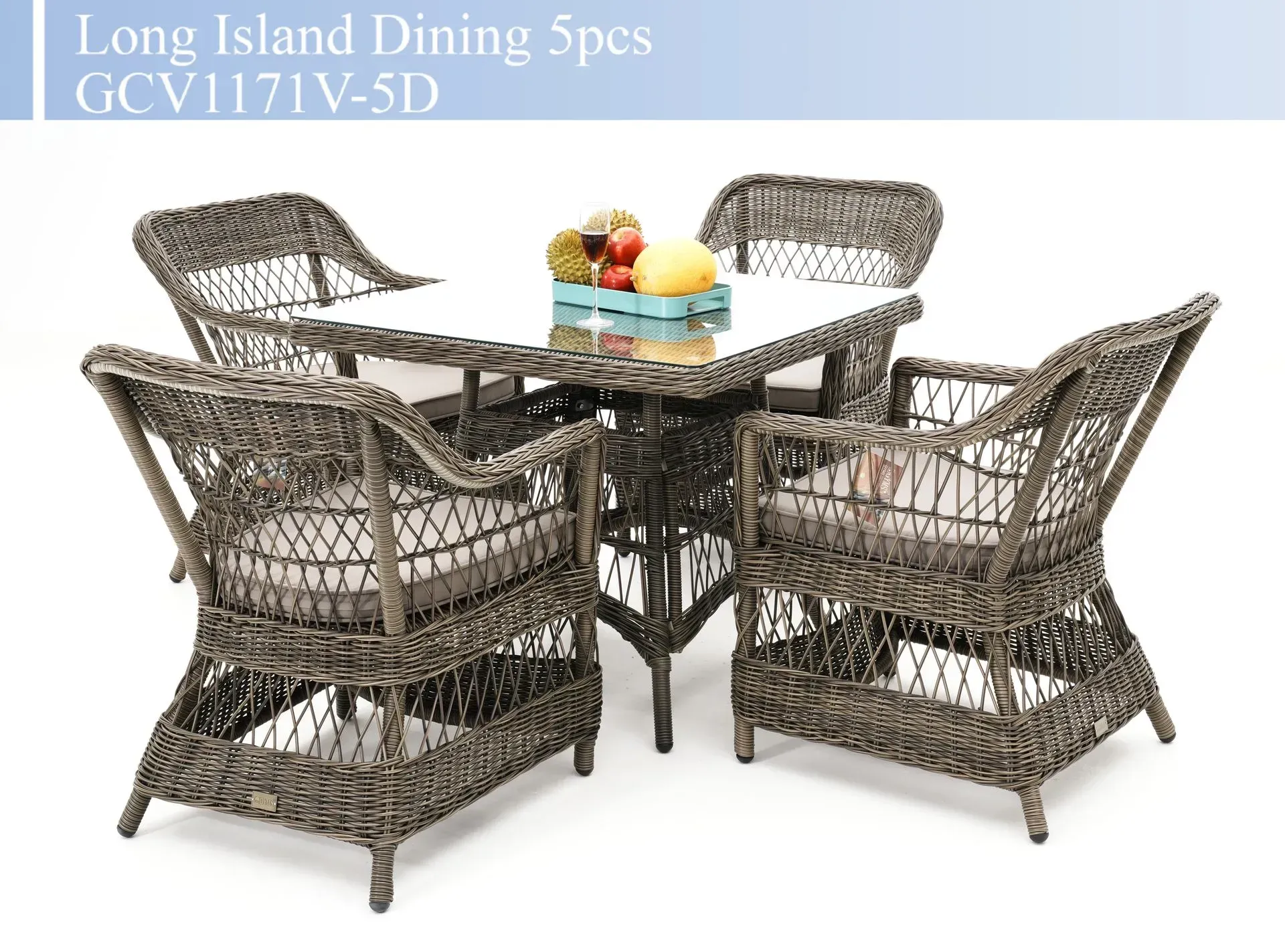 Wicker patio dining set with glass-top table, four armchairs, and colorful fruit centerpiece