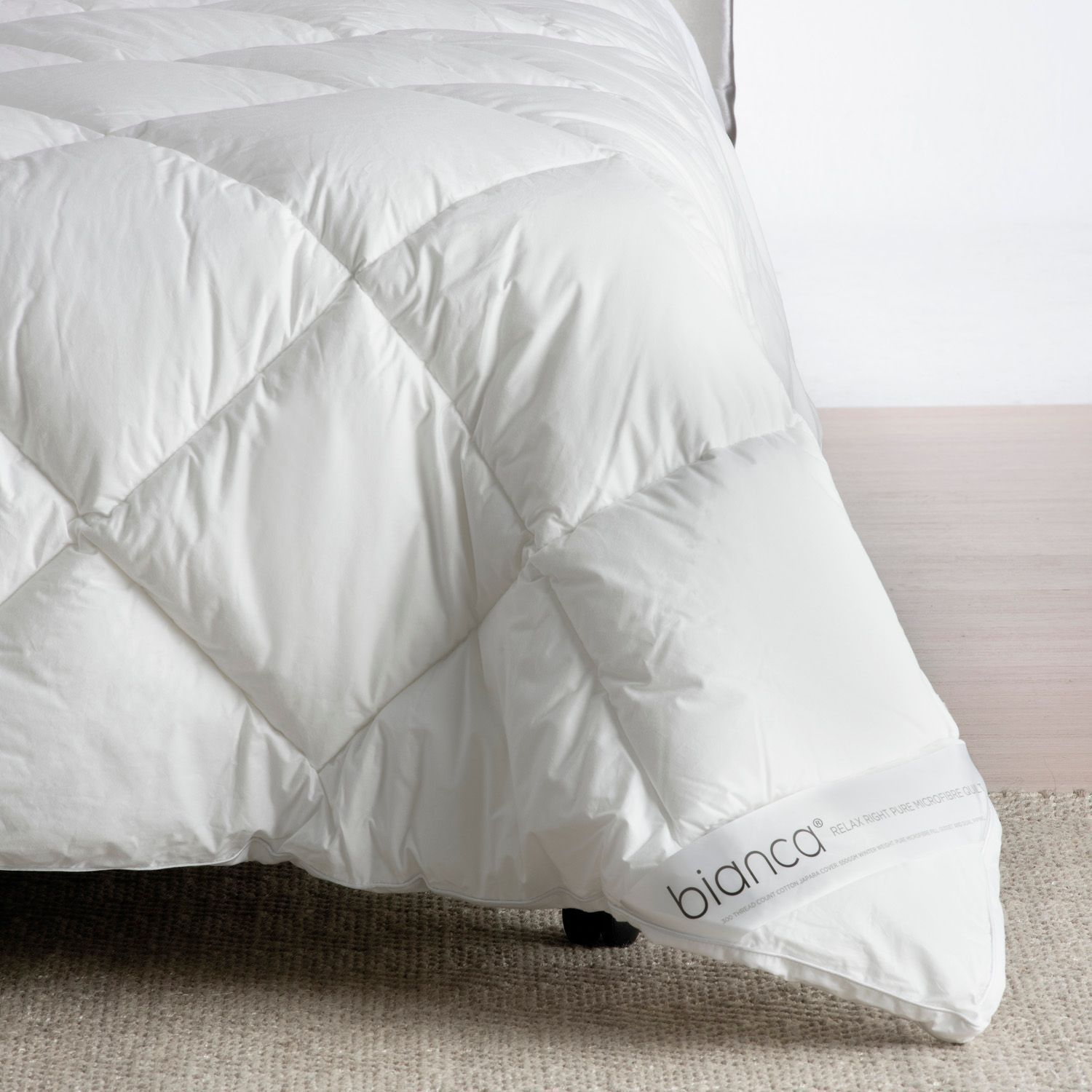 White quilted comforter with a corner label on a bed