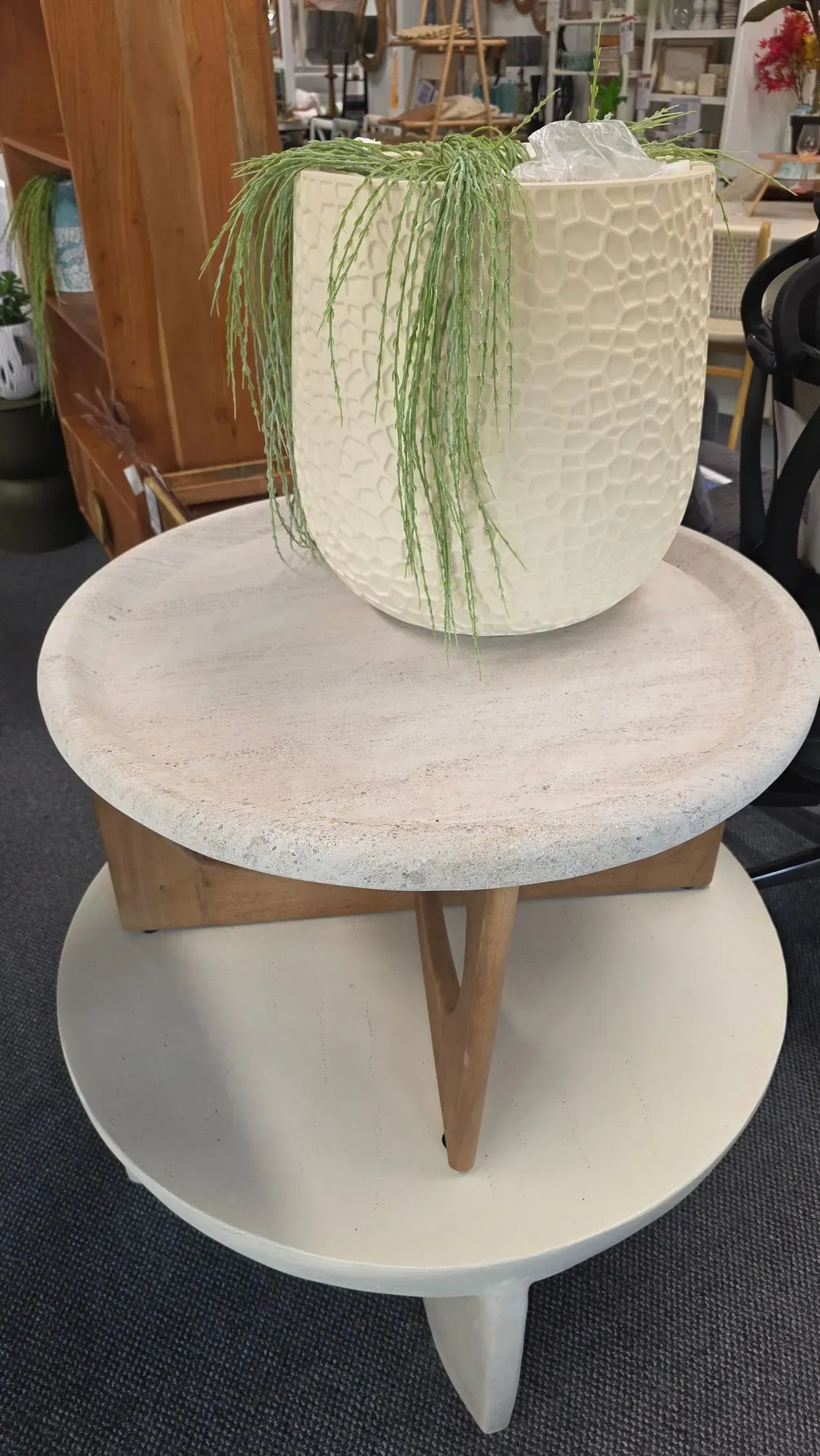 Tiered white pedestal shelf with a textured white vase and trailing green plant on top