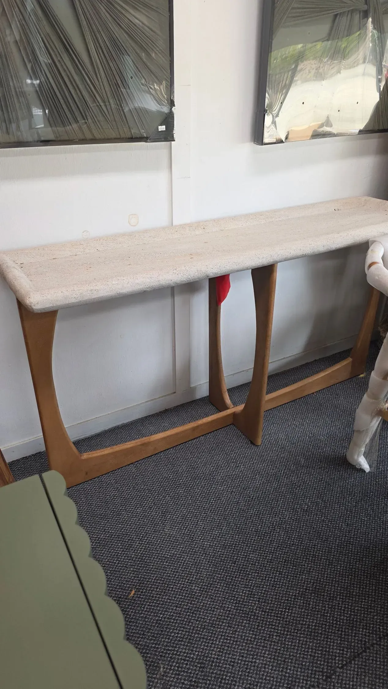 Narrow beige console table with speckled top against a wall, over a dark patterned rug.