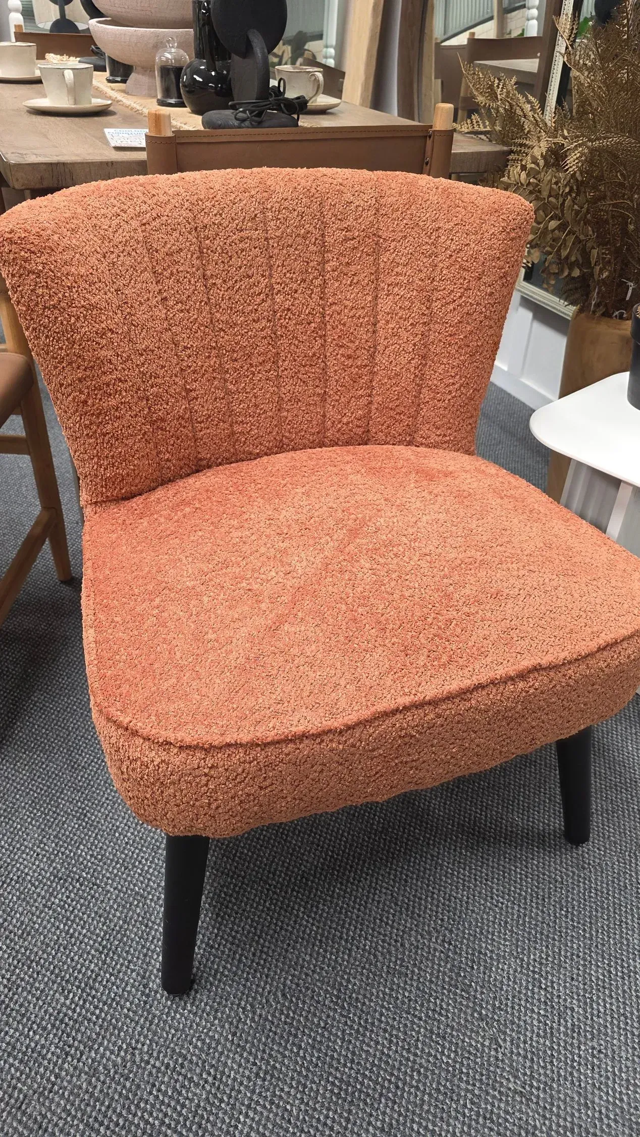 Orange upholstered accent chair on a gray carpet in a furniture showroom