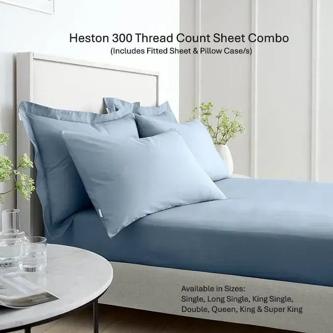 Blue bed sheet and pillowcase set on a neatly made bed in a bright bedroom.