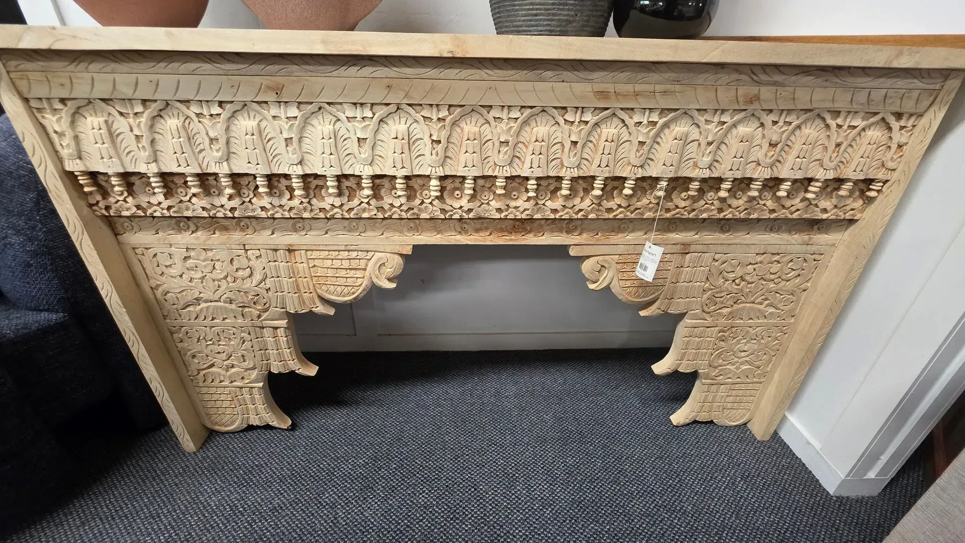 Ornate carved wooden panel leaning against a wall on carpet flooring