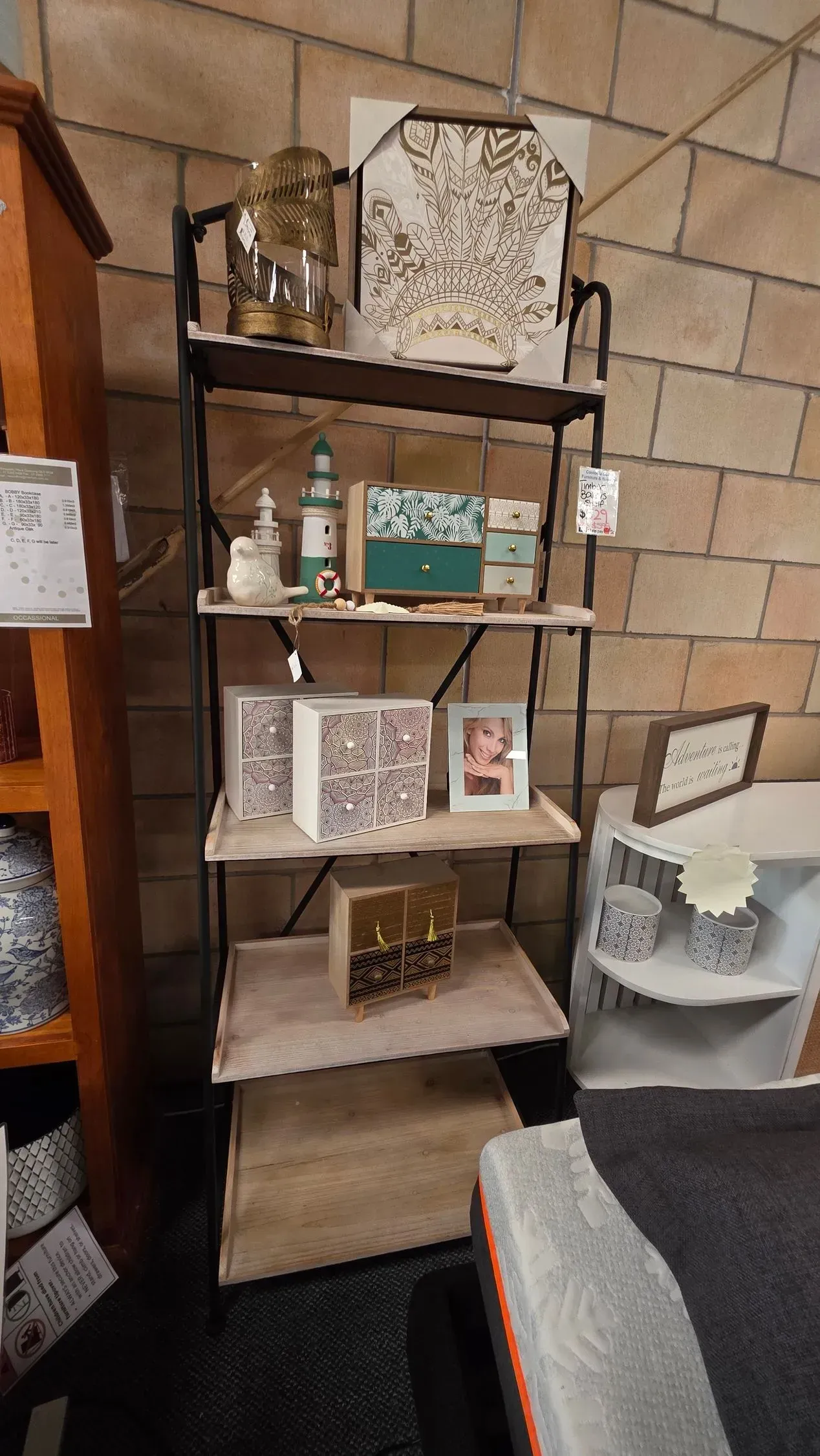 Tall wooden shelf with home decor items, including patterned boxes and a framed photo, in a tiled room.