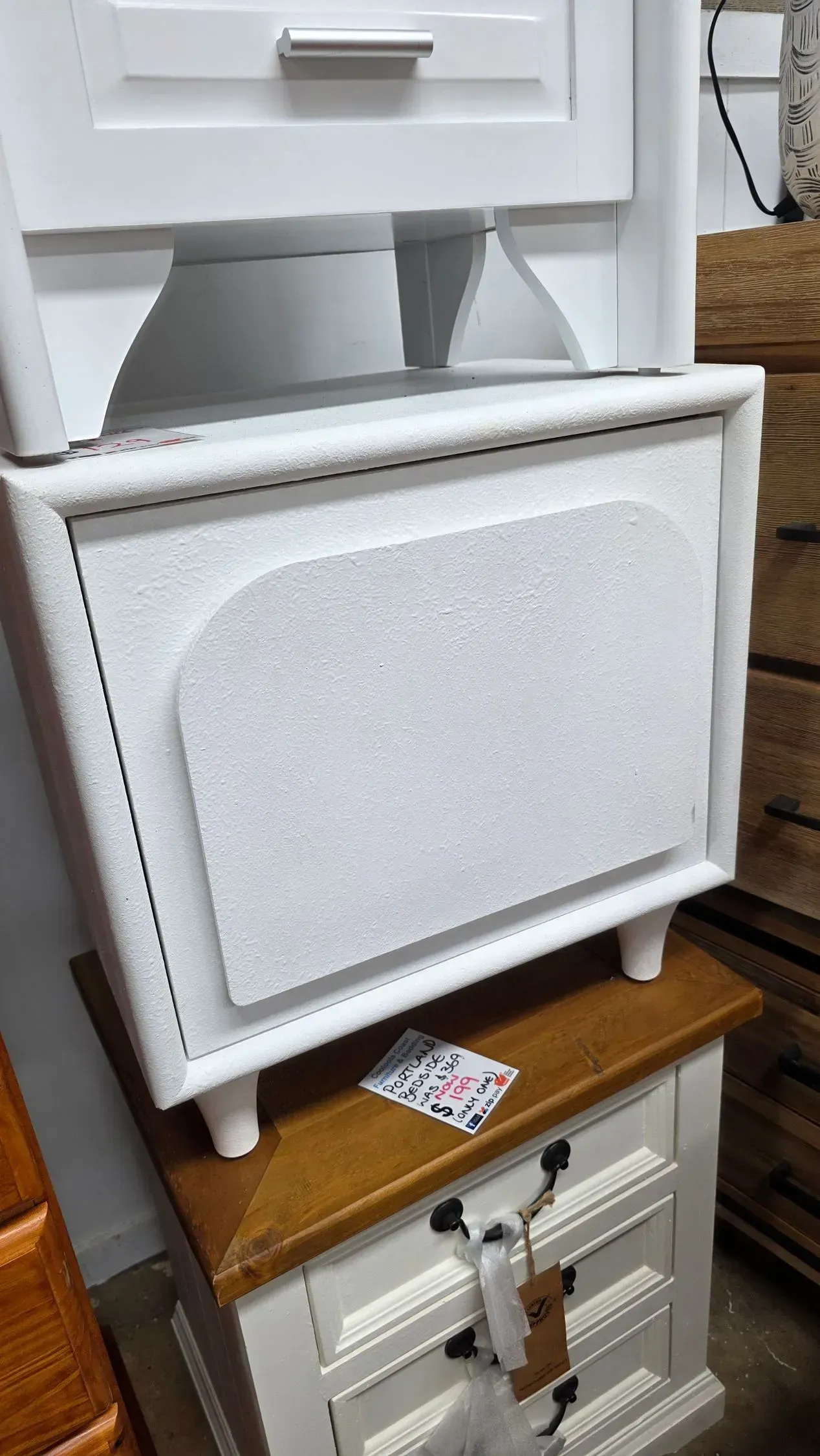 White folding step stool with padded seat in a small bathroom, resting on a wooden cabinet.