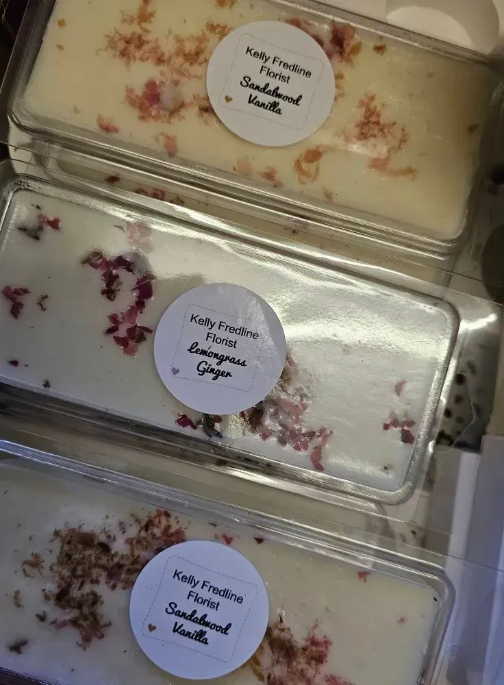 Three labeled dessert containers with cream-topped sweets and scattered flower petals in clear trays